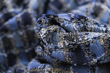 Close-up of textured fabric of blue color with a pattern of black, white and beige threads. ...