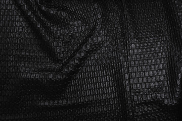 Texture of black Gagliano fabric with oval pattern, top view.  Background, texture of draped suit fabric with shiny oval pattern.