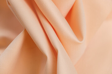 Close-up of texture of cotton fabric of peach sorbet orange color. Background, texture of draped fabric without patterns.