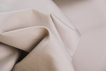 Close-up of texture of cotton fabric in silver-beige color. Background, texture of draped fabric without patterns..