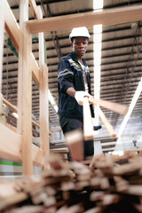 Multiracial worker standing in warehouse examining hardwood material for wood furniture production. Engineer wear safety hardhat uniform working in lumber pallet factory. Supervisor check merchandise