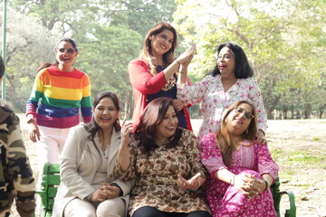 Reunion of happy Indian women. green park lush green atmosphere. tranquil and serene environment. elderly old friends together. three women in park having fun in day time. ladies enjoying.