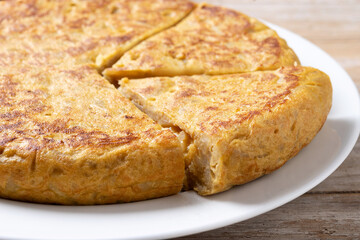 Traditional spanish omelette with ingredients on wooden table.
