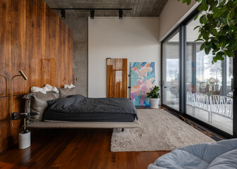 Bedroom in house with hardwood flooring, large bed, and sliding glass doors