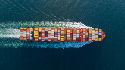 Aerial top view of cargo ship with contrail in the ocean sea ship carrying container and running...