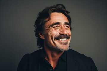 Handsome mature man laughing and looking at camera on grey background