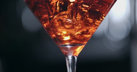 Super slow motion close up of fresh cool crystal ice cubes being put by bartender in transparent glass with elegant alcoholic cocktail during preparation for customer in bar or disco club at 1000 fps.