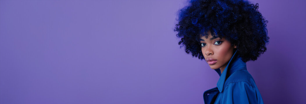 A woman with blue hair and a blue shirt is standing in a field of purple flowers. model with blue afro hair wearing a blue trench in a full body photoshoot like wild flower composition blue and purple