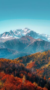 A breathtaking view of a vast mountain range in autumn, showcasing vibrant fall colors on the trees and bushes. The mountains loom tall in the background under a clear sky.