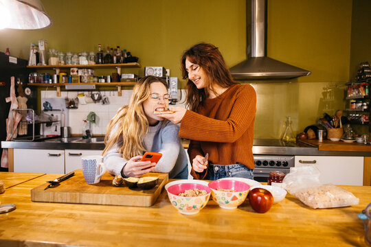 A lesbian couple preparing breakfast and sharing a toast, in the cozy atmosphere of their kitchen at home. - Powered by Adobe