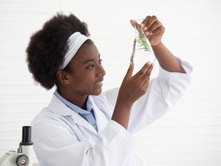 A dark-skinned student smiled happily as she shows the results of the experiments on plants in the science lab. Science and education, researcher and discovery concept.