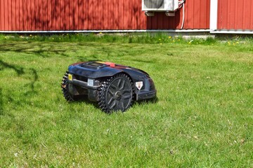 The lawnmower robot mows the grass in the garden.	