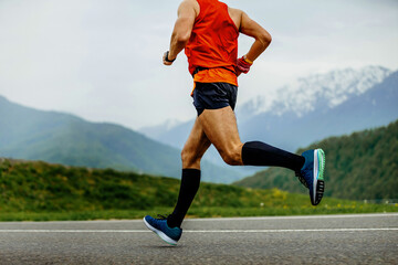 male athlete running mountain marathon on asphalt in black compression socks