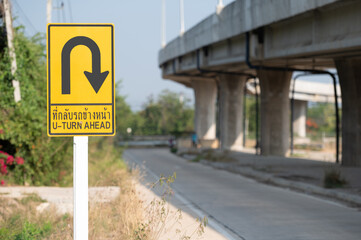 Selective focus of Thailand U-turn ahead sign.Background is public road. 