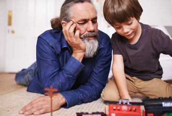 Grandfather, kid and play with toy, train and fun in home or house with joy. Mature man, child and...