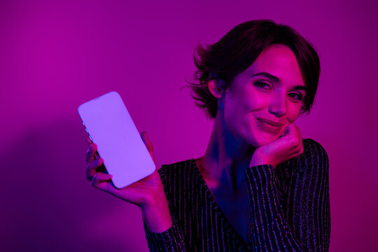 Photo portrait of attractive young woman hold white screen dressed stylish overall clothes isolated on neon light pink color background