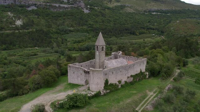 Aerial drone view of Church of the holy trinity (Cerkev Sv. Trojice) surroundeded by a wall, Hrastovlje, Koper, Slovenia.