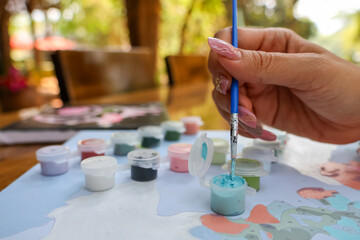 Phukan watercolor in the hands of a middle-aged Asian woman practicing painting in her free time to...