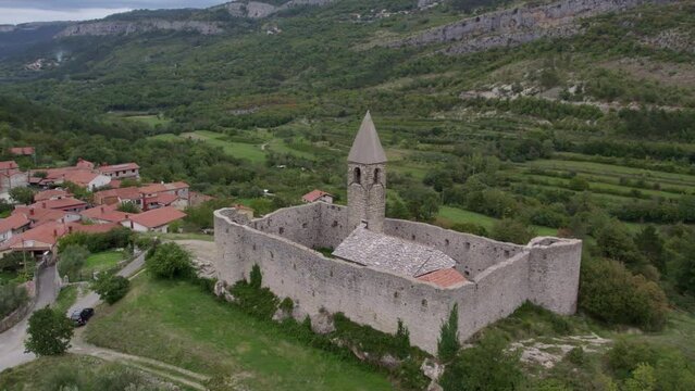 Aerial drone view of Church of the holy trinity (Cerkev Sv. Trojice) surrounded by a wall, Hrastovlje, Koper, Slovenia.