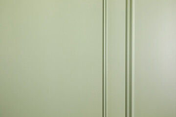 A wall covered with light green paint and molding