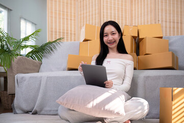 Asian woman small business entrepreneur working from home use tablet for commercial inspection. online marketing Packaging box, concept ecommerce