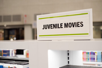 Juvenile movies collection on shelves displays at public library in Texas, diverse wide variety of DVD, Blu-ray, CD, multimedia, visualization digital content for teenager interactive learning