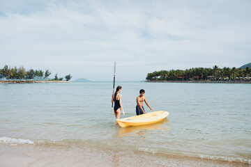 Carefree Asian Couple Kayaking on Tropical Lake: Fun-filled Leisure and Togetherness amidst Beautiful Nature