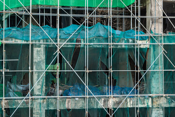 An old on-hold or abandoned hi-rise tower resuming construction. Scaffolding covering the weathered...