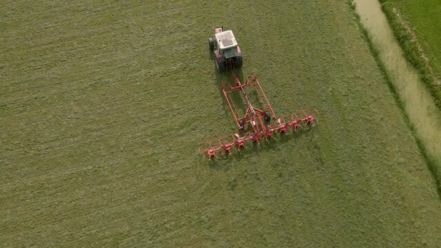 Aerial view of tractor turns the grass with a hay rake attached, Friesland, Netherlands