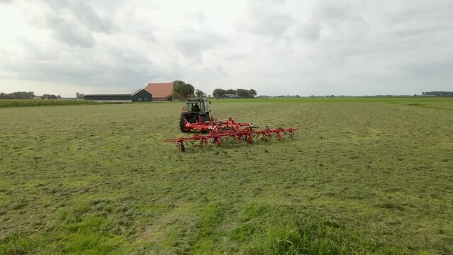 Aerial view of tractor turns the grass with a hay rake attached, Friesland, Netherlands