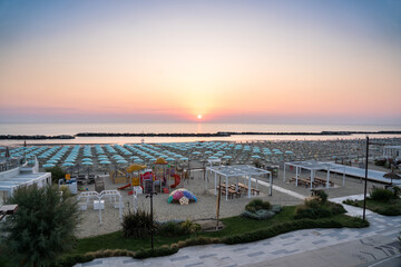 Beautiful sunrise on Rimini beach with umbrellas - obrazy, fototapety, plakaty