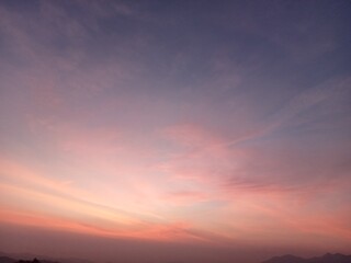The sky has purple-orange tones in the early morning as the sun rises over the mountains