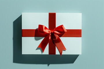 Weiße Karte mit roter Schleife vor farbenfrohem Hintergrund: Festliches Geschenkkonzept