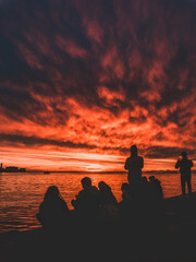 Silhouette of a bunch of friends watching a spectacular red sunset in Trieste