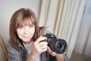 Senior old elderly woman with black camera with a large lens indoors in the studio. A professional...