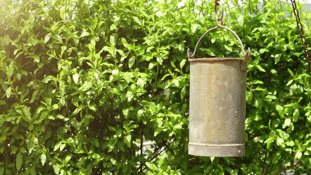 Metal bucket swings in wind near well