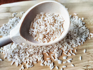 Rice scattered on textured fabric and in a wooden spoon. Grits for cooking. Texture, background, copy space and place for text