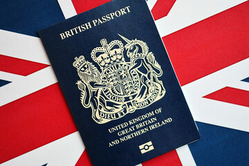 Blue British passport on national flag background close up. Tourism and citizenship concept - obrazy, fototapety, plakaty