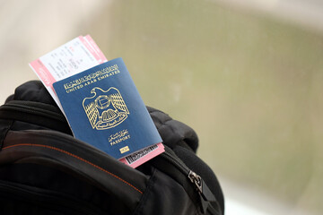 Blue United Arab Emirates passport with airline tickets on touristic backpack close up. Tourism and travel concept