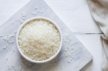 turkish raw white rice grains in bowl or spoon on table, healthy food uncooked legumes concept