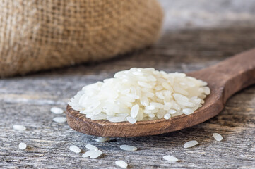 turkish raw white rice grains in bowl or spoon on table, healthy food uncooked legumes concept