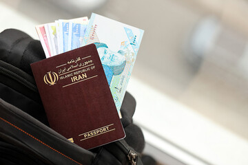 Red Islamic Republic of Iran passport with money and airline tickets on touristic backpack close up. Tourism and travel concept