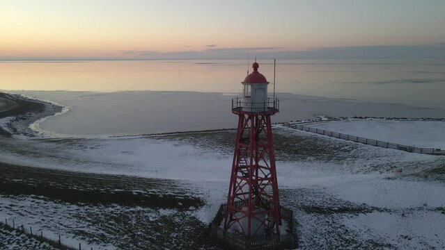 Aerial view of lighthouse at lake during sunset with snow, Stavoren, Netherlands