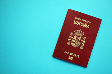 Red Spanish passport of European Union on blue background close up. Tourism and citizenship concept
