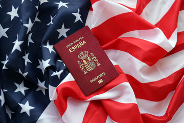 Red Spanish passport of European Union on United States national flag background close up. Tourism and diplomacy concept - obrazy, fototapety, plakaty