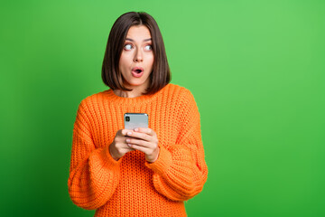 Portrait of impressed crazy lady hold smart phone open mouth look empty space isolated on green color background