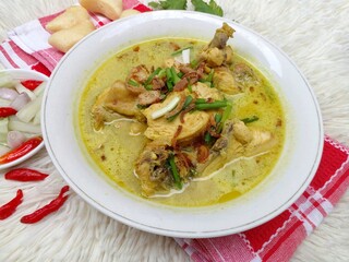 Gulai ayam or chicken curry served in a white bowl. A soupy dish made from chicken cooked with spices and coconut milk. Indonesian traditional cuisine.