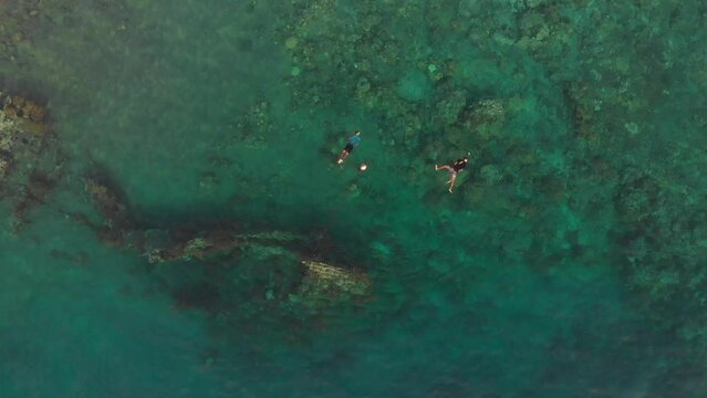 Aerial view of shipwreck in blue water with swimmers, Amed, Bali, Indonesia