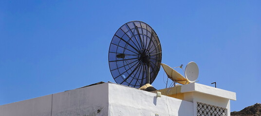 Communication Contrast: Satellite Dishes Against Clear Sky, Modern Technology On Traditional Rooftop