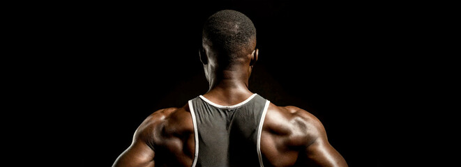 Close-up of a muscular black man, back view of a bodybuilder athlete, isolated on a black background with copy space. Generative Ai.